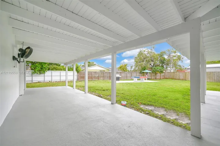 Covered patio featuring an exposed-beam ceiling, concrete flooring, and a fenced backyard