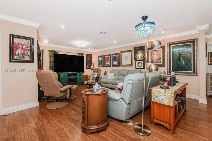 Living area featuring wood-finish flooring, crown molding, and recessed lighting