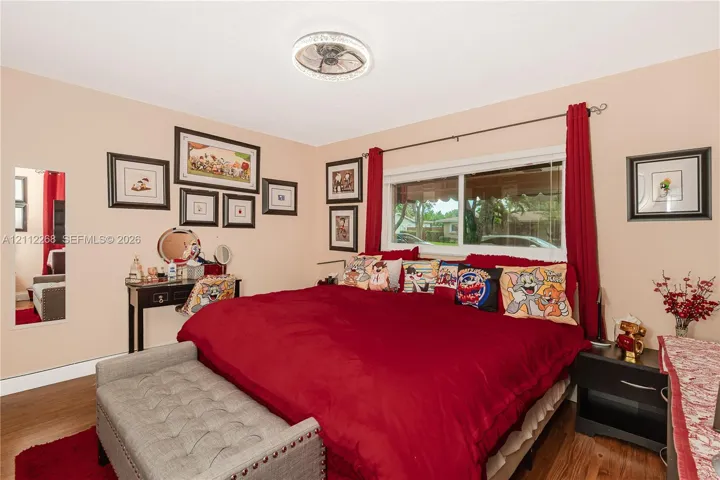 Room featuring wood-finish flooring, a ceiling-mounted light fixture with integrated fan, and a large horizontal sliding window