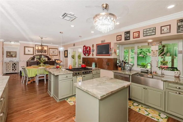 Kitchen featuring a large central island, custom cabinetry, a professional-style gas range, farmhouse-style sink, and stone-finish countertops