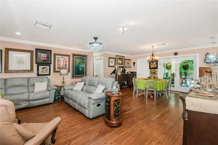 Wood-finish flooring, crown molding, multi-pane glass double doors, crystal-style chandelier, and recessed lighting