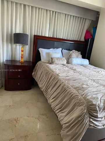 Light-toned stone flooring and floor-to-ceiling curtained wall featuring a recessed valance