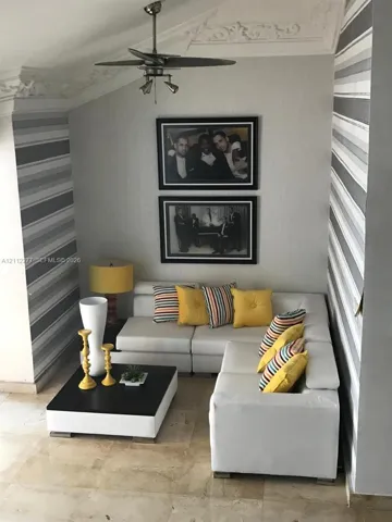Room featuring striped accent wall covering, ornate crown molding, polished stone flooring, and a ceiling-mounted light fixture with integrated fan