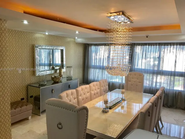 Tray ceiling with recessed lighting, custom crystal pendant fixture, stone flooring, and textured wallpaper