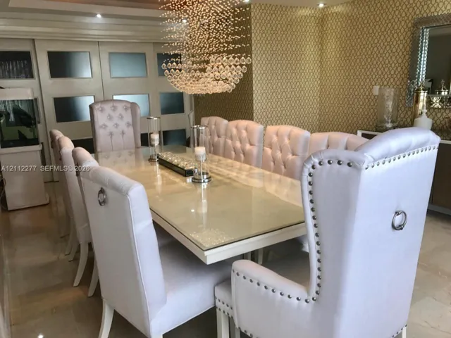 Crystallized multi-tier chandelier, textured patterned wall covering, recessed ceiling lighting, and multi-panel frosted glass sliding doors