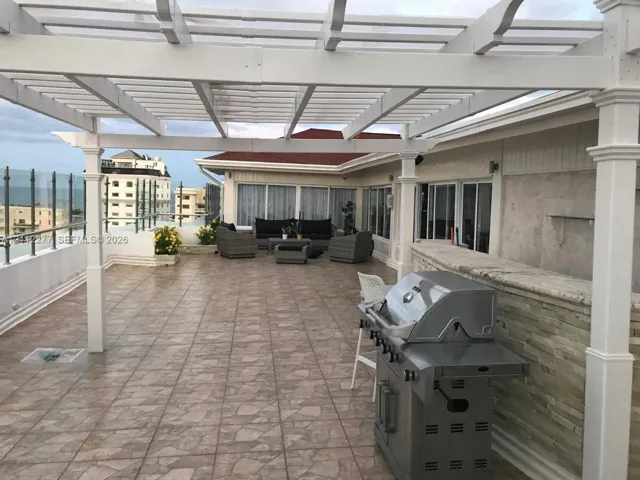 Rooftop terrace featuring tile flooring, a white pergola, a stacked stone bar, and glass panel railing