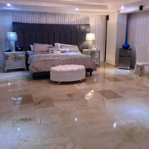 Polished stone flooring, recessed ceiling lighting, and floor-to-ceiling drapery