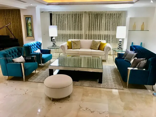 Polished stone flooring, recessed ceiling with crown molding, and built-in glass shelving