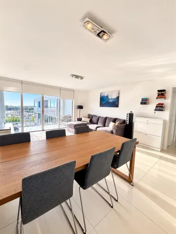 Open-concept living space featuring floor-to-ceiling glass sliding doors, polished tile flooring, and dual modern rectangular flush-mount ceiling light fixtures