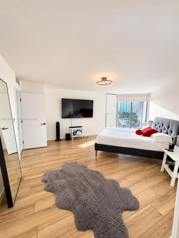 Wood-finish flooring, flush-mount circular lighting, and sliding glass doors leading to a balcony