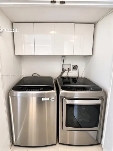 Laundry area featuring white high-gloss upper cabinetry and a wall-mounted fold-out drying rack