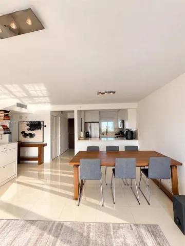 Open-concept interior featuring polished tile flooring, white cabinetry, stainless steel appliances, and flush-mount ceiling lighting