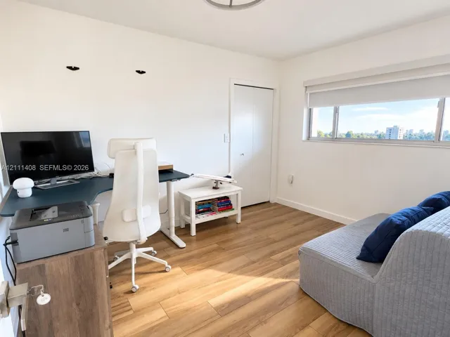 Room featuring wood-finish flooring, a horizontal sliding window with roller shade, and a bi-fold closet door