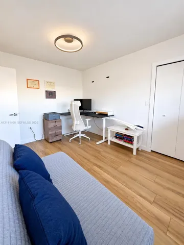 Room featuring wood-finish flooring, a circular modern flush-mount light fixture, and a built-in closet with double-panel doors