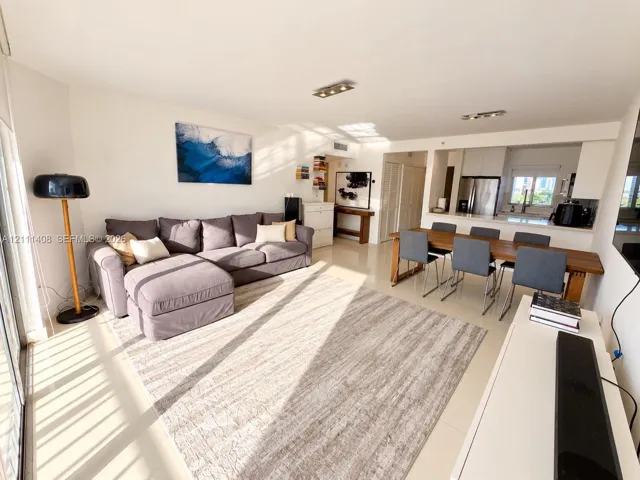 Open-concept floor plan featuring neutral tile flooring, recessed track lighting, and a kitchen equipped with stainless steel appliances