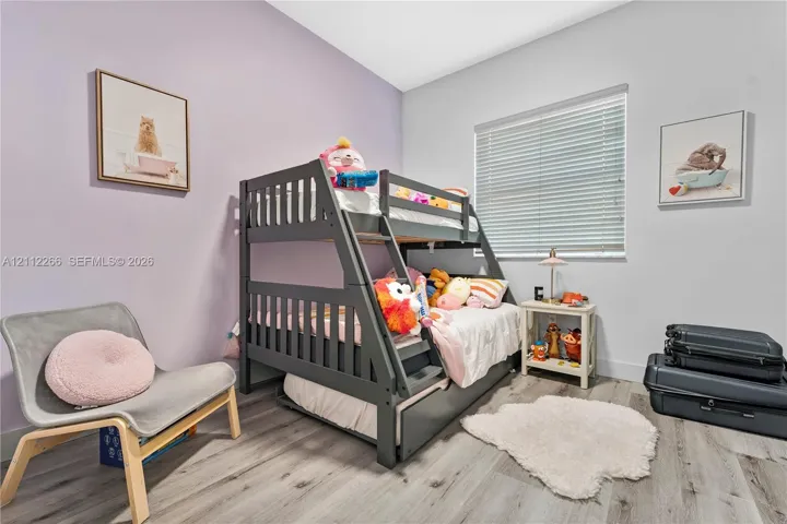 Room featuring wood-finish flooring, a horizontal slat window blind, and two-tone wall paint
