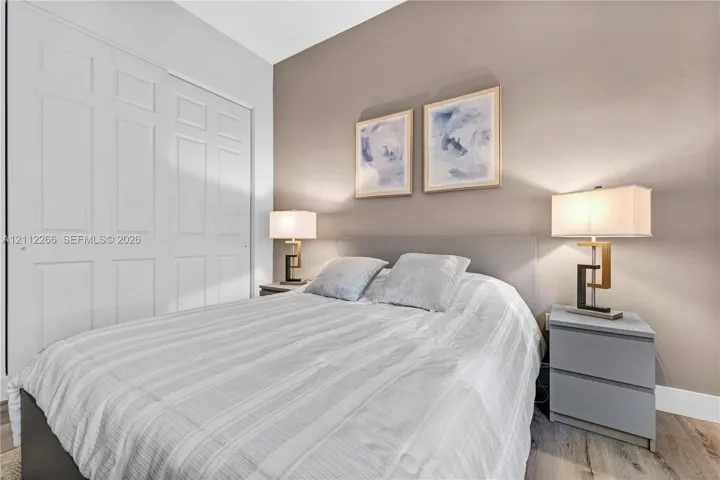 Neutral-toned room featuring wood-finish flooring, a bi-fold closet, and a painted accent wall