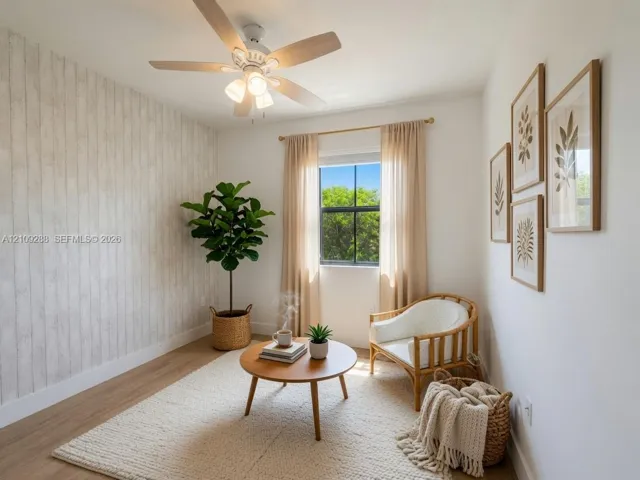 Room featuring wood-finish flooring, a textured vertical-plank accent wall, and a multi-blade ceiling fan with integrated lighting
