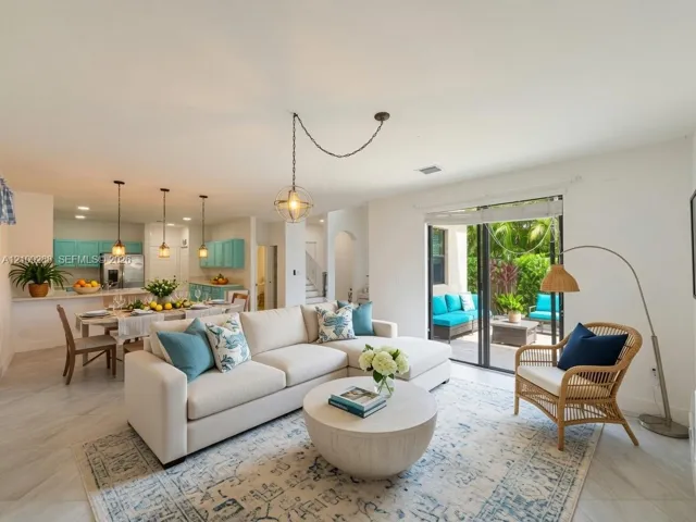 Open-concept living space featuring large-format tile flooring, a hanging geometric pendant light, kitchen cabinetry, and sliding glass doors