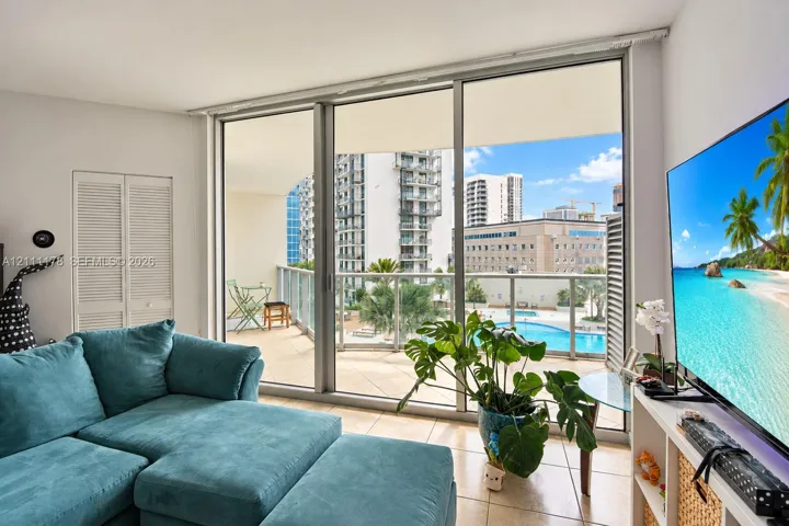 Floor-to-ceiling sliding glass doors, tile flooring, and an expansive balcony with metal railing