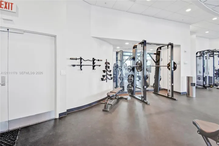 Fitness center featuring rubberized flooring, mirrored walls, and built-in wall-mounted barbell racks