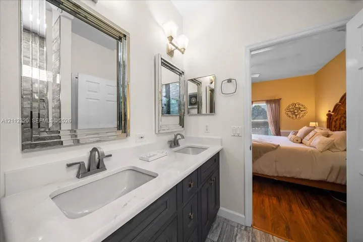 Dual-vanity cabinet featuring a white stone countertop, undermount sinks, brushed-metal fixtures, and framed mirrors