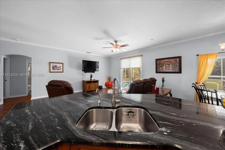 Kitchen island featuring a dark stone countertop, undermount stainless steel double-basin sink, and a pull-down gooseneck faucet