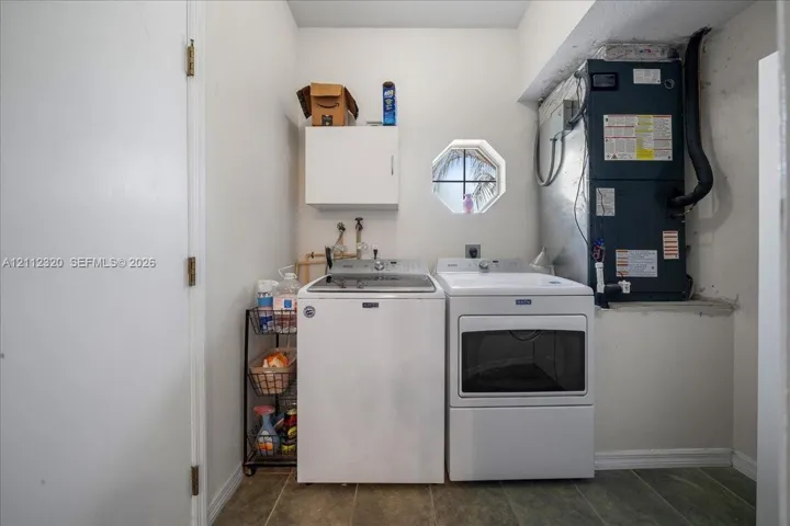 Utility area featuring ceramic tile flooring, an octagonal window, and white wall-mounted cabinetry