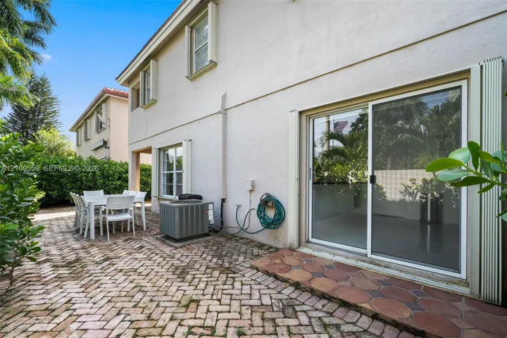 Exterior patio area featuring a herringbone brick floor, large sliding glass door, and stucco wall finish