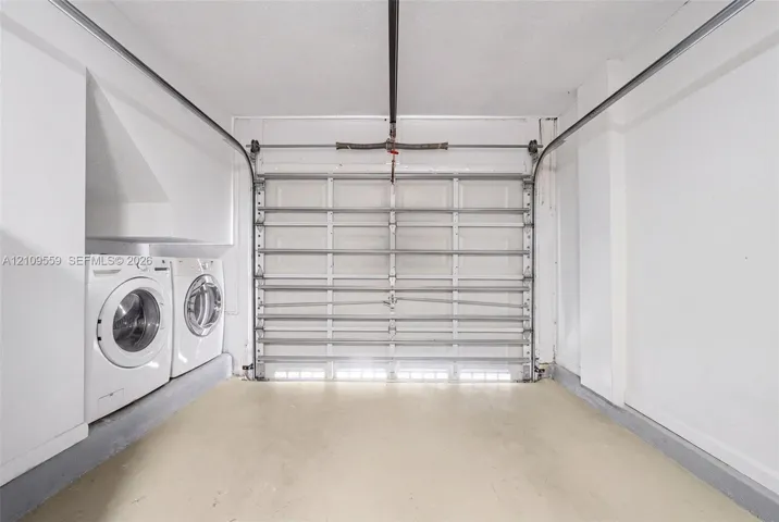 Garage featuring an overhead sectional door, concrete flooring, and built-in laundry hookups