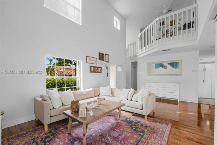 Two-story living area featuring vaulted ceilings, a prominent multi-pane window, and an interior balcony with a white railing