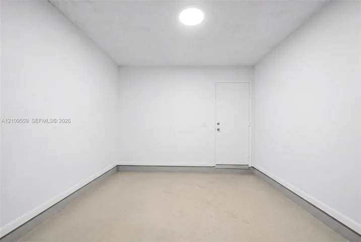 Finished garage interior featuring smooth white-painted walls, a clean concrete floor, and a flush-mounted ceiling light fixture