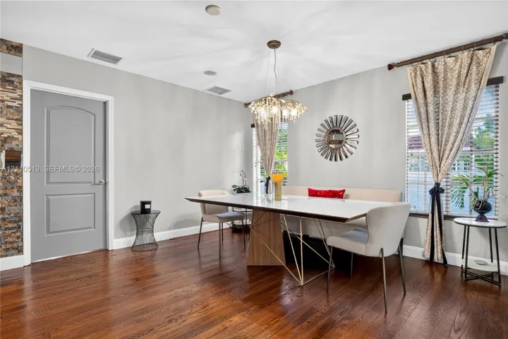 Wood-finish flooring, multi-faceted crystal pendant lighting, stacked-stone accent wall, and arch-top door