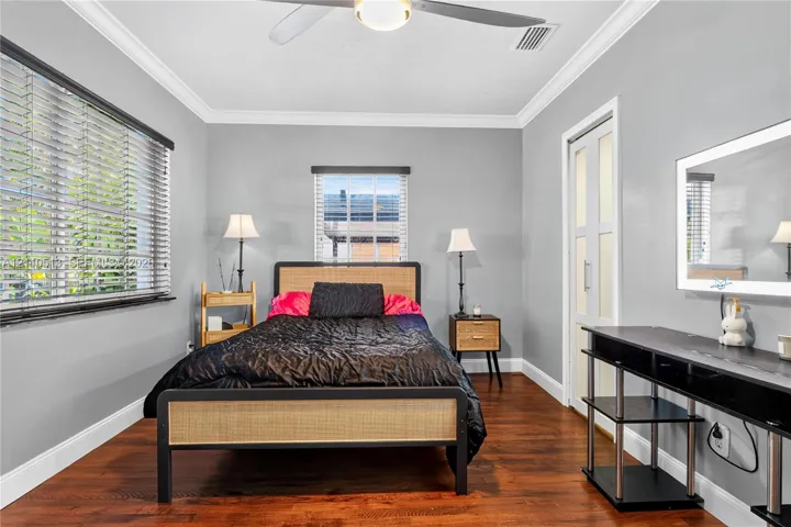 Room featuring wood-finish flooring, crown molding, dual-pane windows with horizontal blinds, and a ceiling fan with integrated lighting