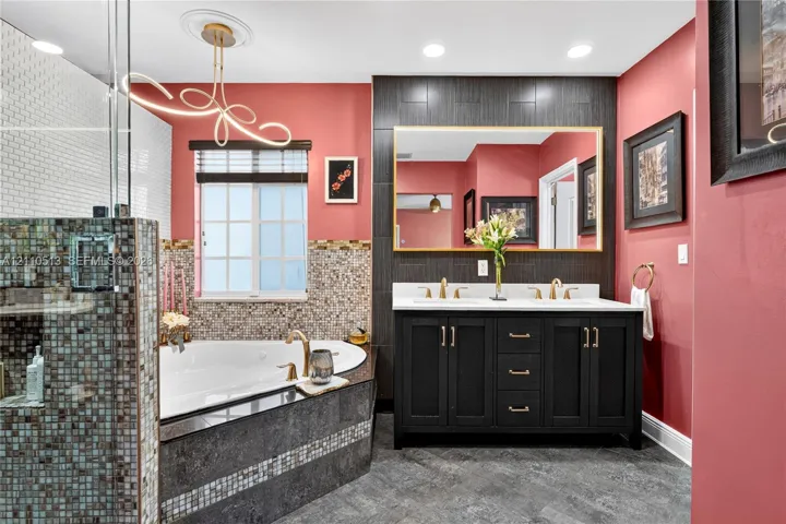 Dual-sink vanity with dark cabinetry, gold-tone hardware, and an oversized rectangular wall mirror
