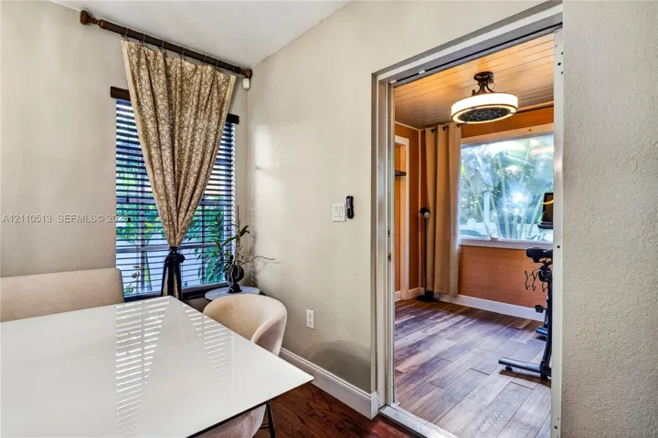 Interior space featuring wood-finish flooring, horizontal window blinds, a tiered ceiling light fixture, and wood-paneled wall accents