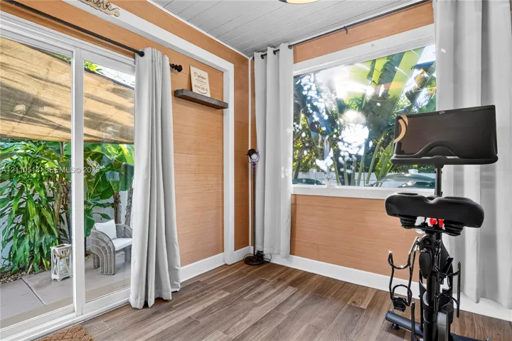 Interior space featuring horizontal wood-finish wall paneling, plank-style wood-finish flooring, a white tongue-and-groove ceiling, sliding glass doors, and a large picture window