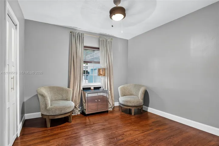 Room featuring wood-finish flooring, a central ceiling fan with an integrated light fixture, and a window with white trim