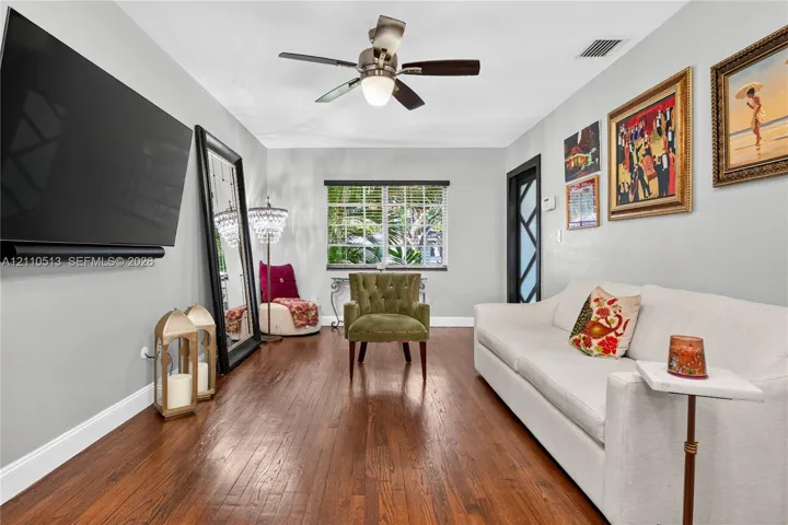 Room featuring wood-finish flooring, a multi-pane window with exterior greenery, and a ceiling-mounted light fixture with a central fan
