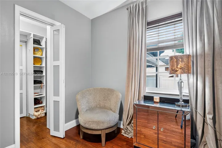 Wood-finish flooring, white framed multi-panel door, and custom built-in shelving unit