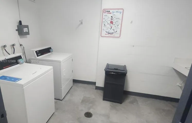 Utility room featuring large-format tile flooring, dedicated washer and dryer hookups, and a built-in wall-mounted sink basin