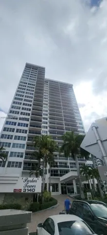 High-rise residential exterior featuring expansive private balconies, a covered porte-cochère entrance, and mature palm landscaping