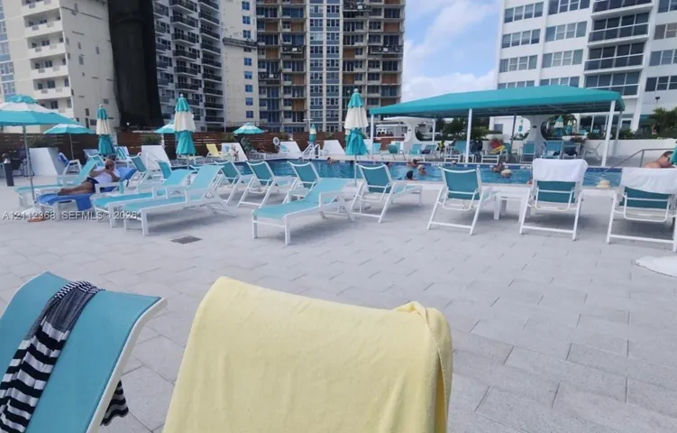 Swimming pool featuring stone-paver decking and a covered shaded patio area