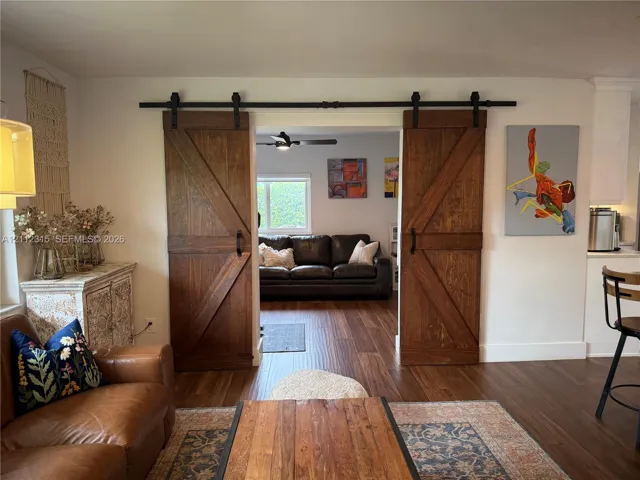 Interior featuring dual sliding wood-finish barn doors with matte black hardware and wood-finish flooring