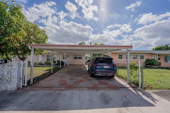 Covered carport featuring a decorative stone-paved floor and a concrete masonry unit fence