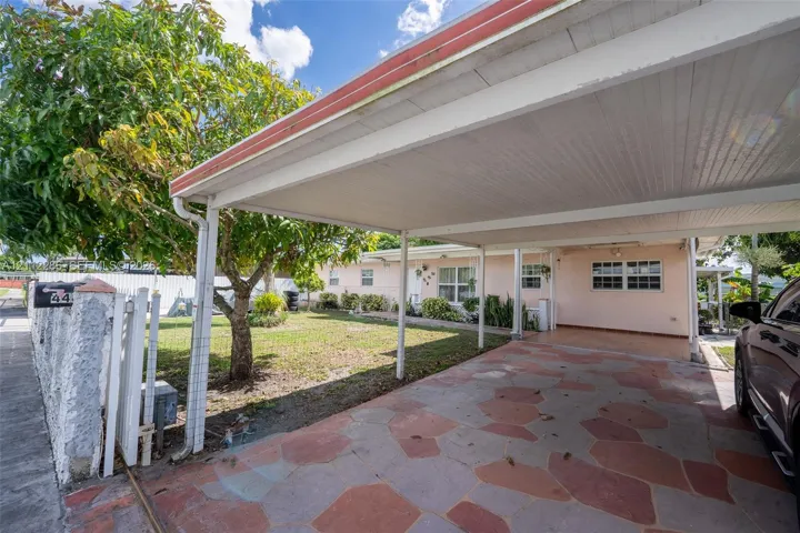Covered carport featuring flagstone paving, integrated outdoor lighting, and a mature tree-lined front yard