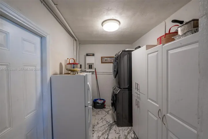 Utility space featuring white shaker-style cabinetry, a dome ceiling light fixture, and patterned tile flooring