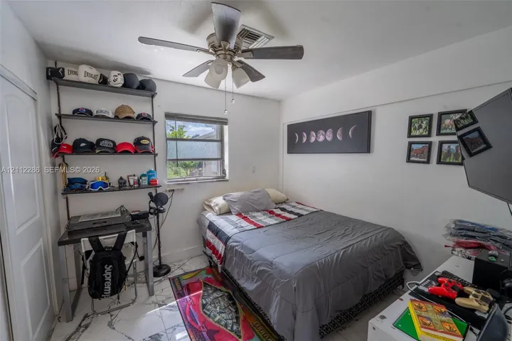 Room featuring white stone-finish tile flooring, ceiling fan with integrated lighting, and a single-pane window with horizontal blinds