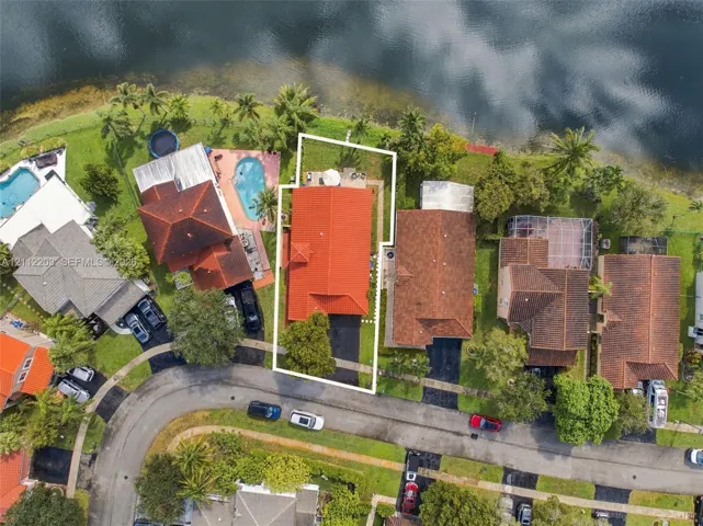 Waterfront residential property featuring a red tile roof, asphalt driveway, and rear yard area