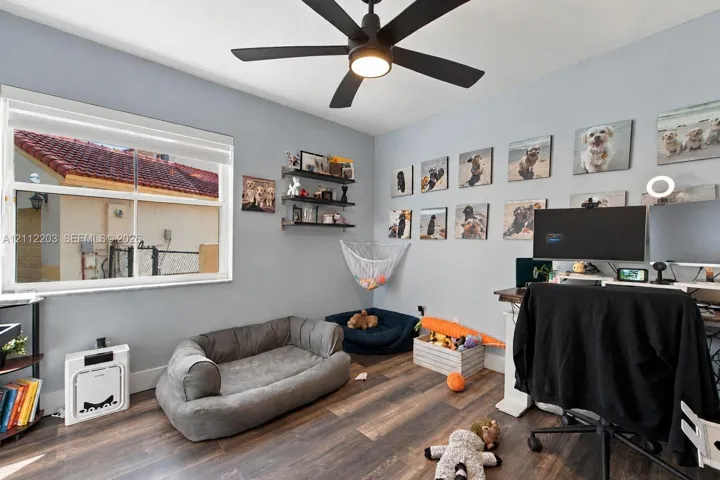 Wood-finish flooring, matte black ceiling fan with integrated lighting, and dual-pane window
